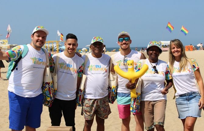 Volunteers in #IEmbrace T-shirts and caps on Copacabana beach, with the Hash mascot balloon